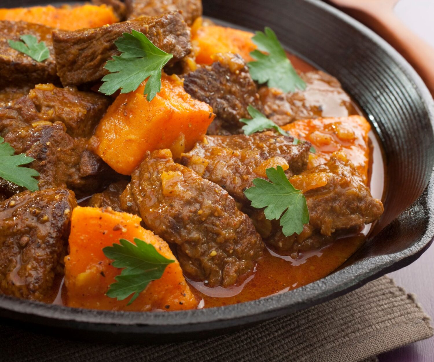 Biergulasch vom Schwein mit Möhren, Sellerie, Zwiebeln in kräftiger Braunbiersoße in der Pfanne serviert