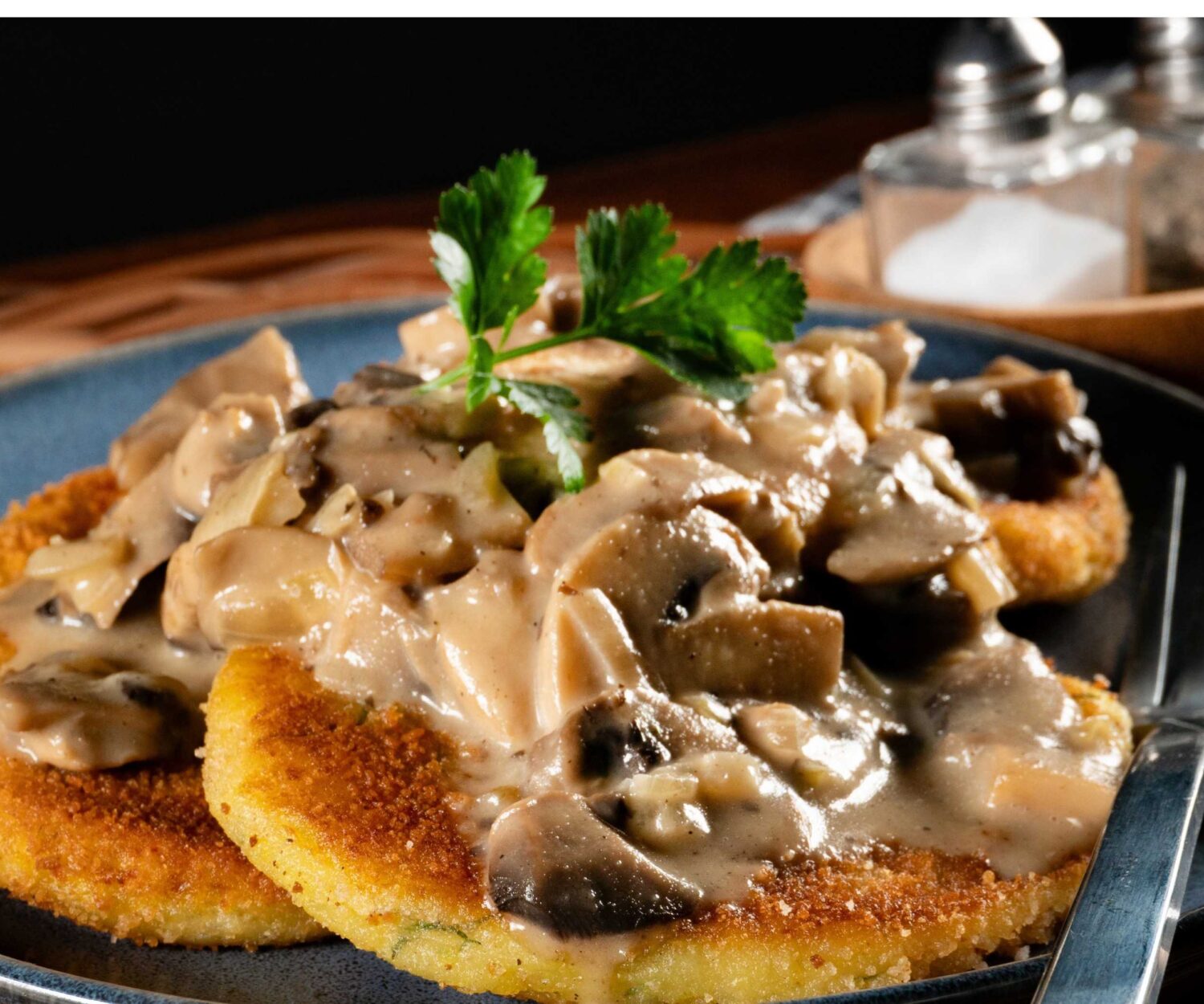 Zwei panierte Schnitzel mit Pilzrahmsoße auf Teller