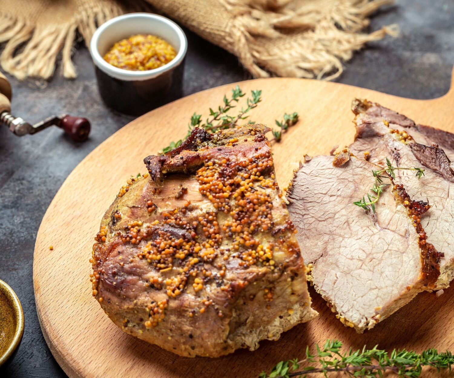 Aufgeschnittener Schweinbraten mit Senfkruste und Thymian anliegend