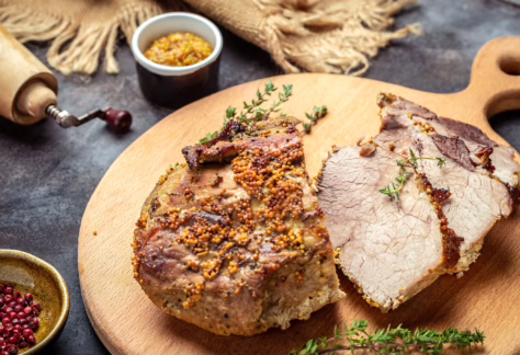 Aufgeschnittener Schweinbraten mit Senfkruste und Thymian anliegend